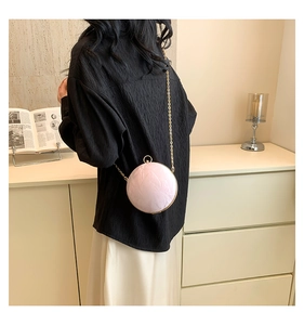 Detail of pink velvet clutch featuring a gold chain strap and metal ring handle