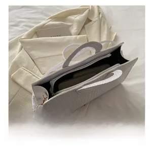 Detail view of the white crocodile texture handbag showing organized internal compartments
