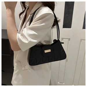 Detail of black quilted shoulder bag with gold clasp and elegant cross-stitch texture