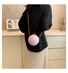 Detail view of pink sphere bag with pleated texture and golden chain on a model
