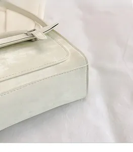 Detail view of smooth matte beige leather texture and fine stitching on stylish messenger bag