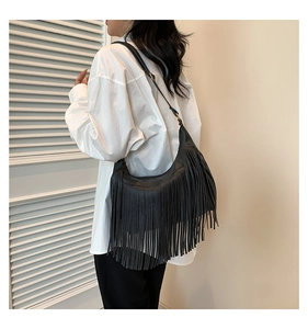 Detailed view of a black Hobo shoulder bag featuring long fringe and adjustable strap