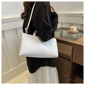 Detail of white crocodile embossed shoulder bag with gold metal feet and sleek handle