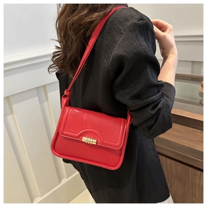 Detailed side view of a red leather shoulder bag with a gold twist lock on a female model