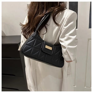 Detail of black quilted shoulder bag with geometric stitching and golden metal buckle