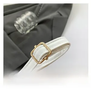 Detail of adjustable white leather shoulder strap with golden square buckle and stitching
