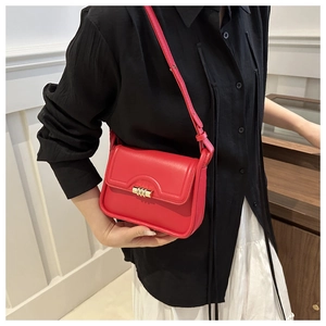 Close-up of red leather flap handbag with gold rotating lock worn by a model
