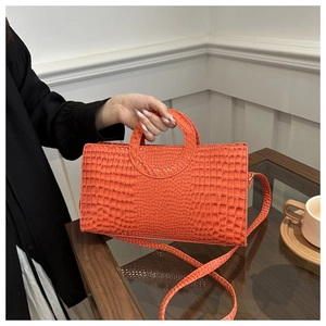 Close-up of orange crocodile pattern handbag featuring a round cutout handle and PU texture