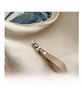 Detailed close-up of durable beige canvas fabric with premium silver metal zipper and puller