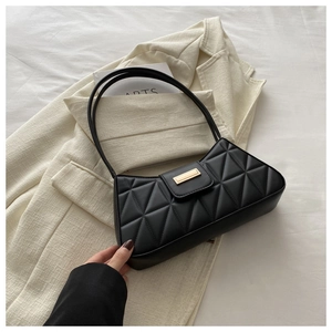 Close-up of black quilted shoulder bag with gold metal buckle and dual slim straps