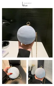 Detail of blue spherical clutch bag with marble texture and gold ring handle