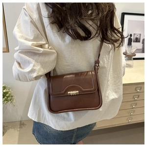 Detailed side view of brown leather crossbody bag with elegant gold metal buckle on flap