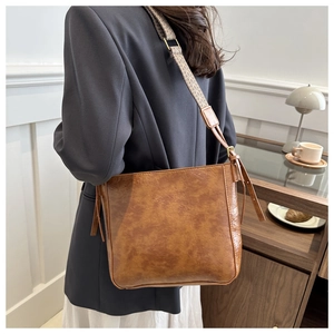 Gros plan d'un sac bandoulière marron vintage avec une large sangle tissée géométrique