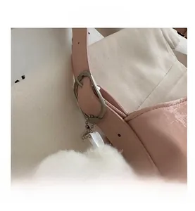 Close-up of pink leather tote bag featuring adjustable strap and white faux fur ball charm