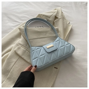 Detail of light blue baguette bag with triangular quilting and gold metal buckle on a blazer