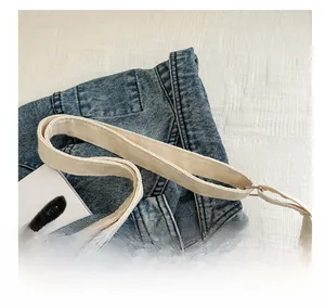 Detail view of durable beige canvas shoulder strap with silver metal adjustment buckle
