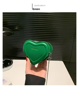 Detail of green heart-shaped mini crossbody bag with gold text and metal chain strap