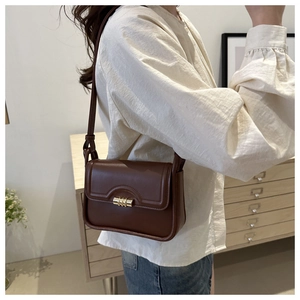 Detailed view of brown PU leather shoulder bag featuring a gold cylinder turn-lock closure