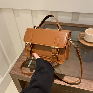 Retro brown minimalist crossbody bag with top handle and twin buckle details on the front