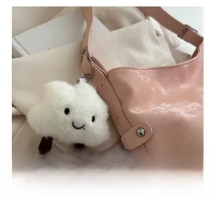Close-up of a cute white plush cloud charm with a smiley face on a pink tote bag