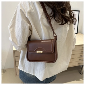 Rear view of brown leather crossbody bag with gold lock worn over a white shirt
