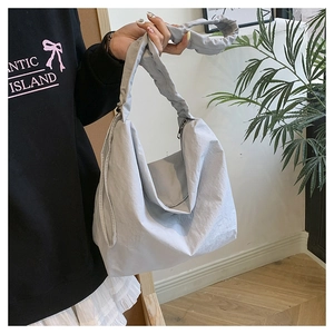 Detail of light blue pleated nylon shoulder bag with cloud-style handle and metal zipper