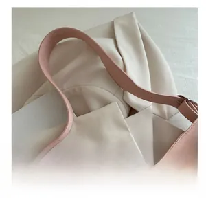 Close-up of pink leather tote bag featuring a wide shoulder strap and silver metal buckle