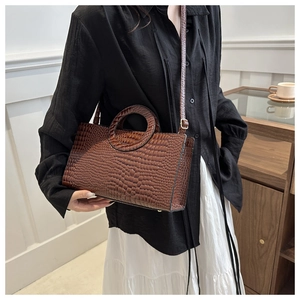 Detail of dark brown crocodile pattern bag featuring unique circular integrated handle