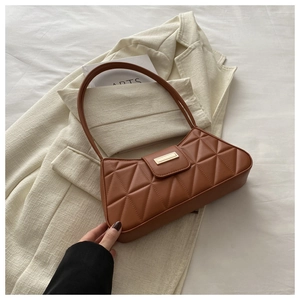 Detail view of brown quilted baguette bag with triangular stitching and gold buckle