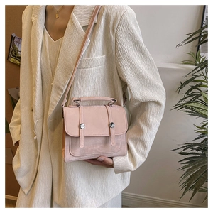 Detailed side view of pink faux suede crossbody bag with vintage vertical straps and buckles