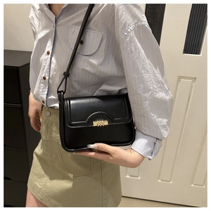 Close-up of black leather flap bag with elegant gold cylindrical lock and shoulder strap
