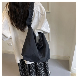 Detail of black cloud drawstring hobo bag with ruched shoulder strap on model