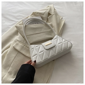 Detail of white quilted baguette bag with geometric patterns and gold metal clasp