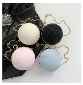 Detailed view of spherical crossbody bags with pleated texture and gold chain straps