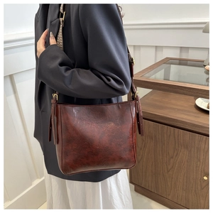 Detail of vintage brown leather bucket bag showing adjustable strap and golden hardware