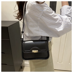 Detail of minimalist black patent leather shoulder bag with cylinder gold metal buckle