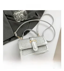Close-up of silver glitter crossbody bag with square flap and golden metallic clasp