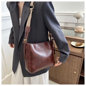 Detail of dark brown leather bucket bag with jacquard strap and brass hardware finish