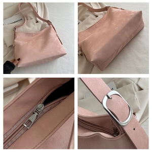 Detail view of pink shoulder bag showing suede texture, silver hardware and strap