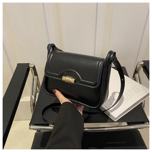 Detail of black faux leather crossbody bag with golden twist lock and adjustable strap