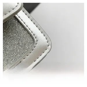 Close-up of glitter silver fabric detail with leather stitching on the mini square bag