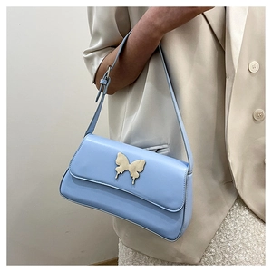 Schicke hellblaue Schultertasche mit goldener Schmetterlingsschnalle zum beigen Blazer