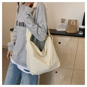 Detail shot of a beige nylon crossbody bag with wide pleated strap in minimalist Korean style