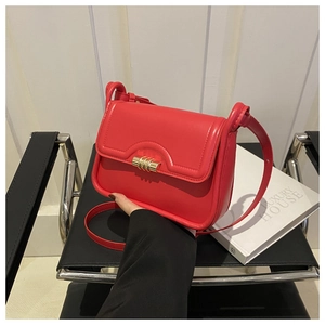 Detail of a red leather handbag featuring a golden metallic twist lock on the front flap