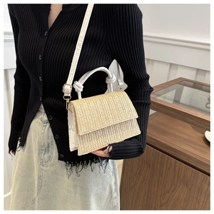 Detail of woven straw handbag with white leather accents and stylish knotted handle