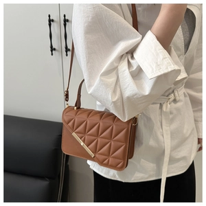 Detail of brown quilted shoulder bag with triangular stitching and gold metal trim