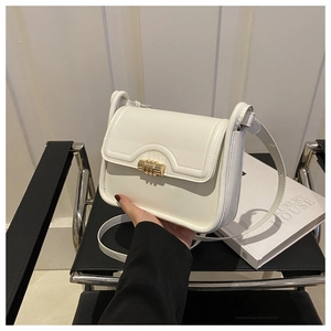 Detailed view of cream white shoulder bag with gold cylindrical metal twist lock