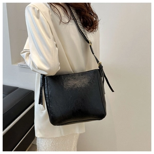 Detail view of a black leather bucket bag with stylish checkered decorative strap on a model