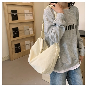 Detail of cream white pleated nylon crossbody bag with drawstring side and zipper closure