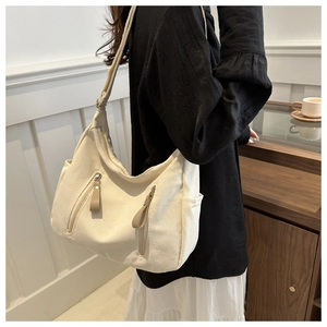 Detail of off-white canvas crossbody bag featuring side pocket and zip pulls